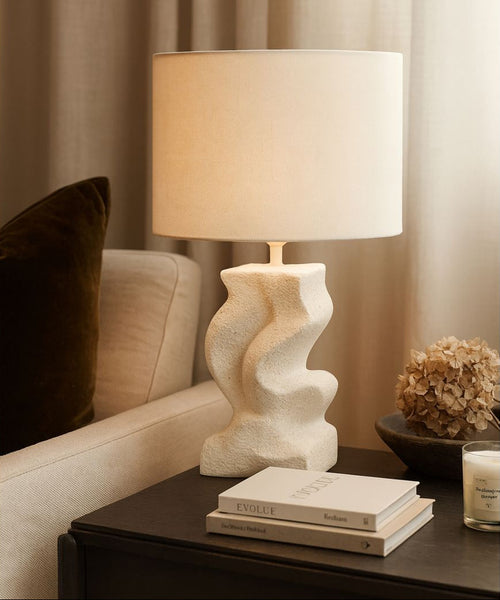 Decorative lamp on a side table next to a sofa with a pillow