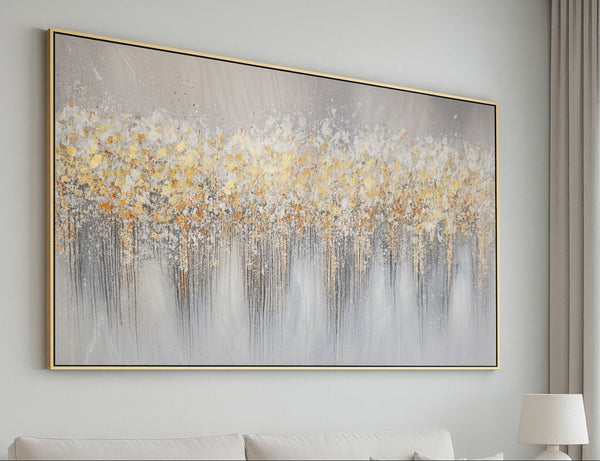 Abstract painting with gold and gray tones on a wall above a sofa.