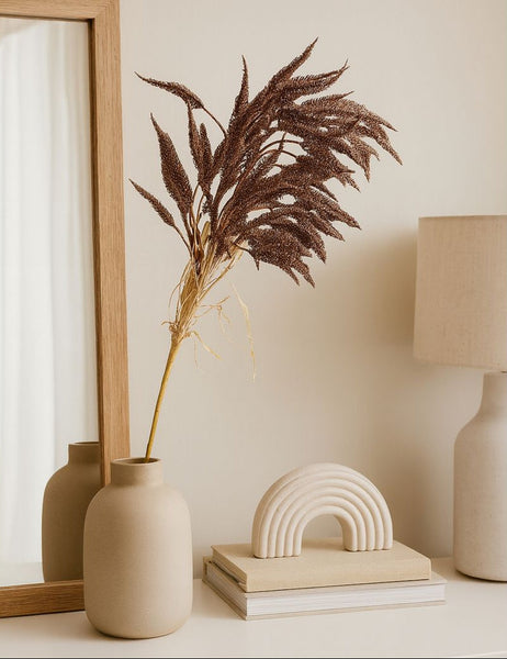 Decorative elements including a vase with dried plants, a lamp, and a small arch-shaped object on a shelf.