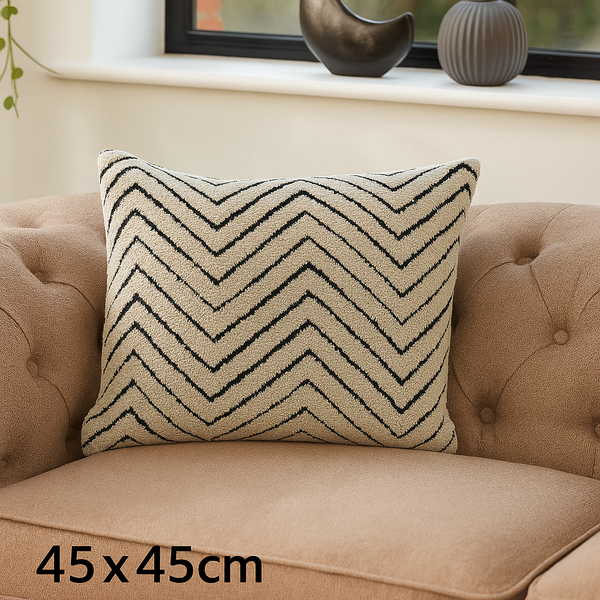 Reese luxury cushion with black chevron pattern displayed on a neutral tufted sofa.