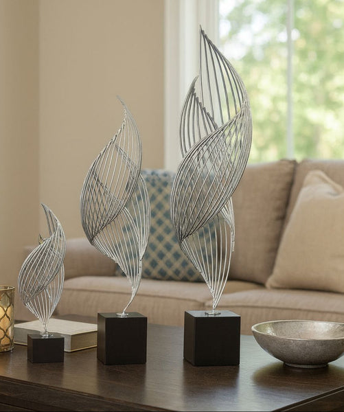 Decorative leaf sculptures on a table with a couch and window in the background