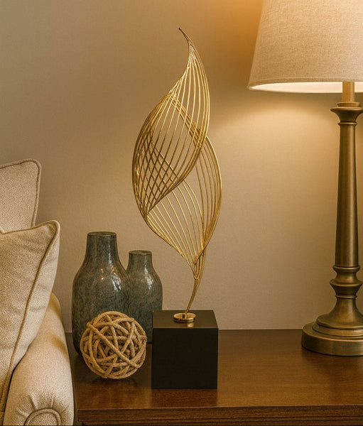 Decorative items including a gold leaf sculpture, textured vases, and a lamp on a wooden surface.