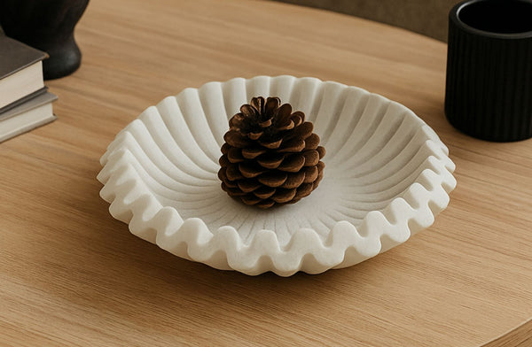 White decorative coastal marble bowl with a pinecone on a wooden surface