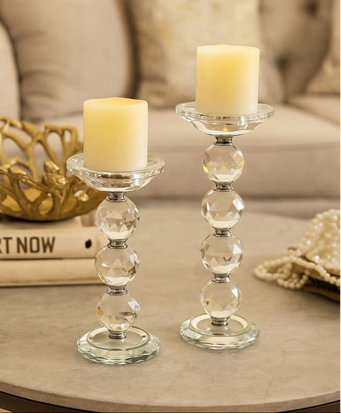 Two candle holders with candles on a table with a beige sofa in the background