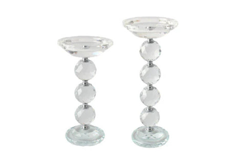 Set of two clear crystal pillar candle holders with faceted sphere design, available in large and small sizes.