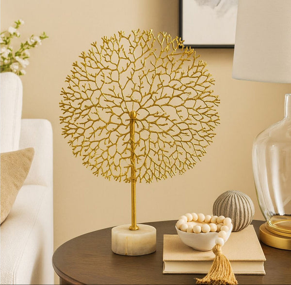 Decorative gold tree sculpture on a table with a neutral background
