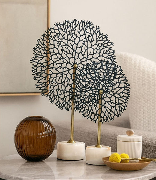 Decorative metal tree sculpture on a table with candles and a vase.