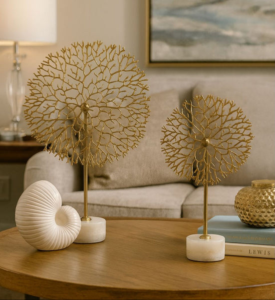 Decorative gold flower stem table decor set on a wooden table with a couch and lamp in the background