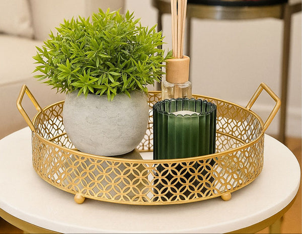 Gold decorative small tray with a plant and candle on a marble surface