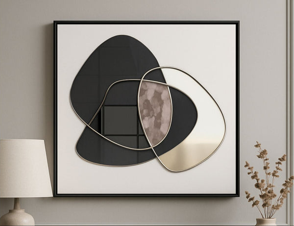 Framed abstract art piece on a wall with a lamp and plant in the background