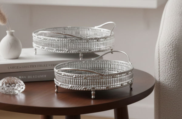 Two silver decorative mirror trays on a wooden table with a neutral background