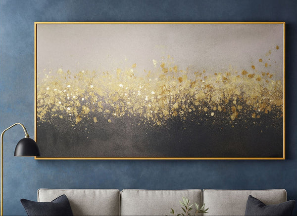 Abstract art piece with gold and black gradient on a blue wall above a gray sofa.