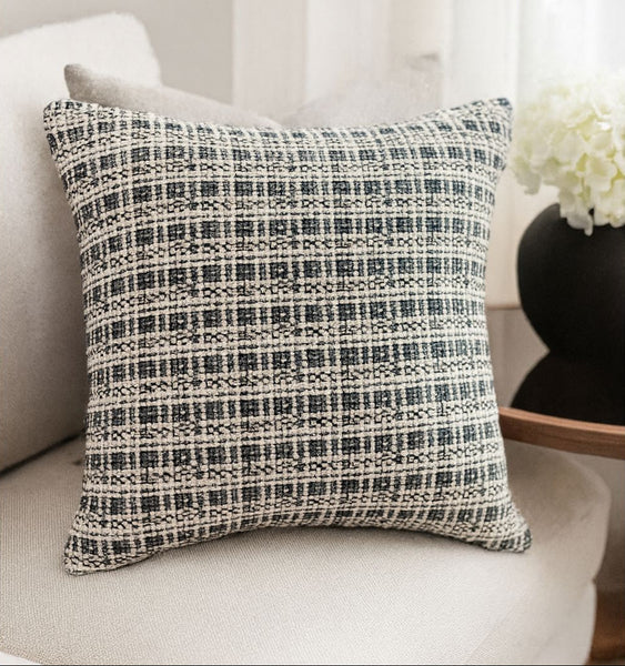 Decorative pillow with a black and white pattern on a white couch.