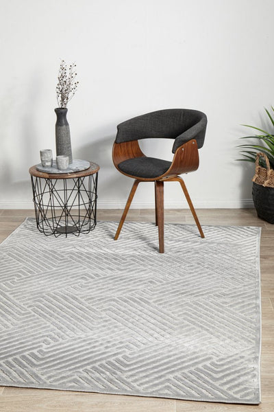 York Cindy Silver Rug styled in a modern living space with chair and side table, showcasing its sophisticated silver hue.