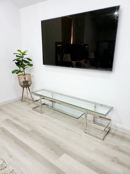 Alexa TV Unit with silver frame and clear glass styled under wall-mounted TV in living