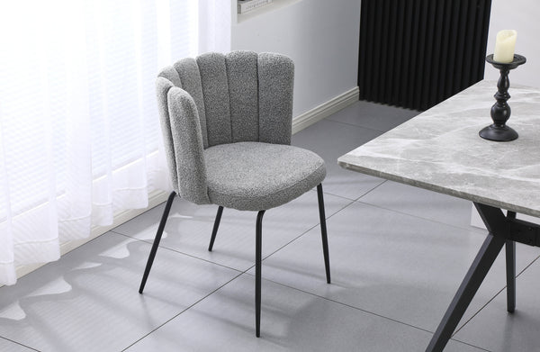 Amelia grey boucle dining chair with black legs styled beside a dining table in a modern room.