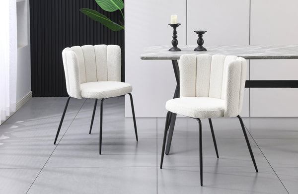 Pair of Amelia off-white boucle dining chairs with black legs styled in a modern dining space.