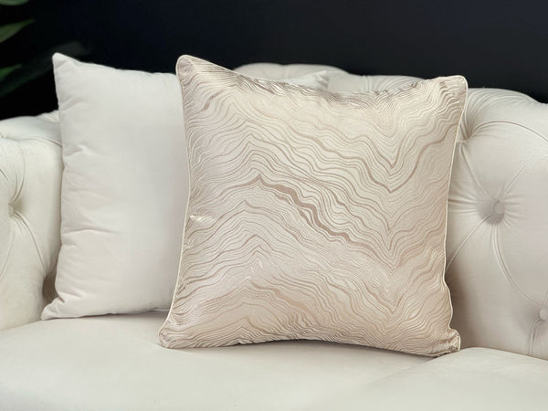 Atlantis Champagne Designer Cushion styled on white sofa, wave textured beige and gold design