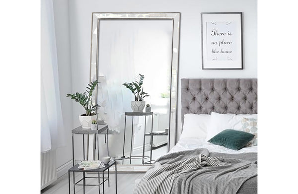 Beaded extra large silver framed mirror styled in modern bedroom with bed and side tables.