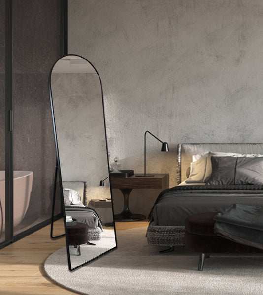 Sleek black free-standing arch mirror in luxury bedroom with neutral tones and modern décor.