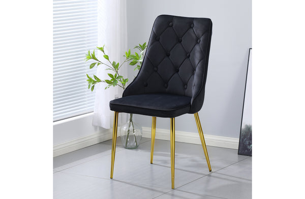 Black velvet button tufted dining chair with gold legs styled in a modern dining space.