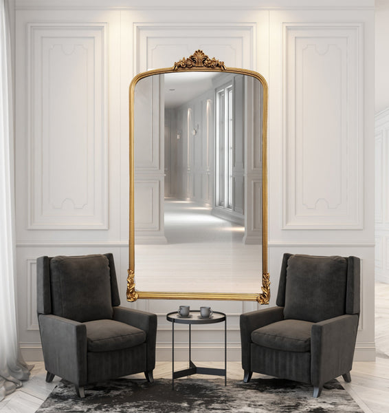 Catherine Gold Lux ornate mirror styled in elegant room with two grey armchairs and décor.
