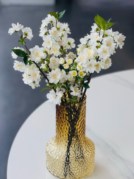 Graceful white artificial cherry blossoms displayed in a stylish vase for a timeless decorative touch.