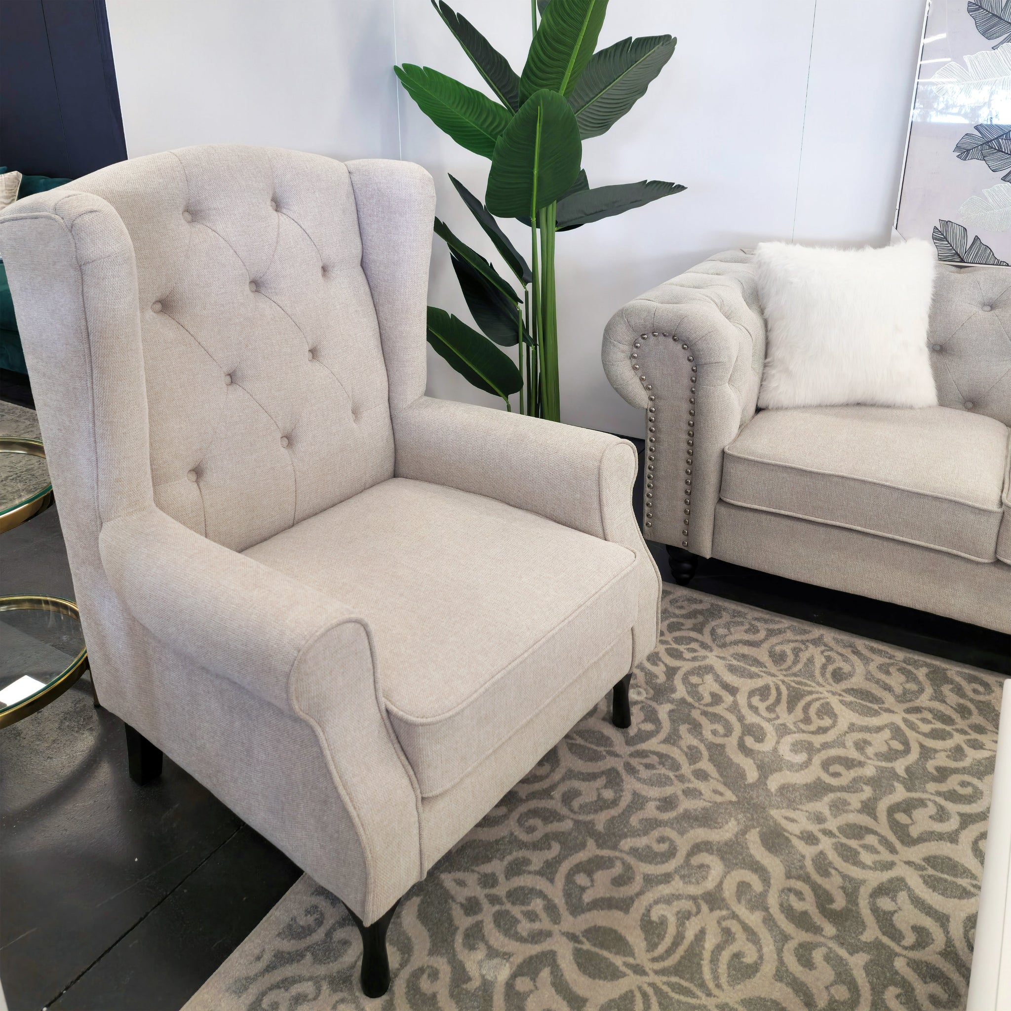 Beige Chesterfield tufted armchair displayed in showroom with matching sofa and rug