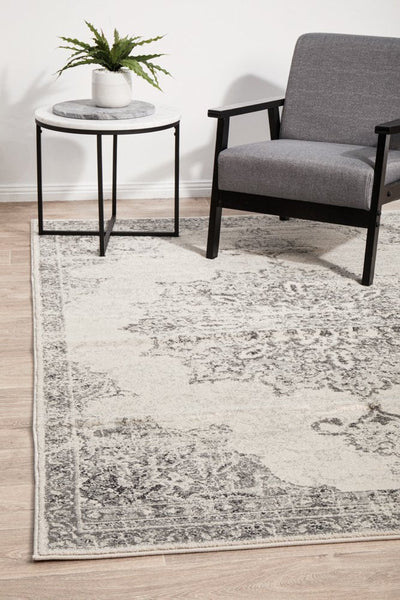 Chrome Rita Silver Rug styled in a modern lounge with a grey armchair and side table.