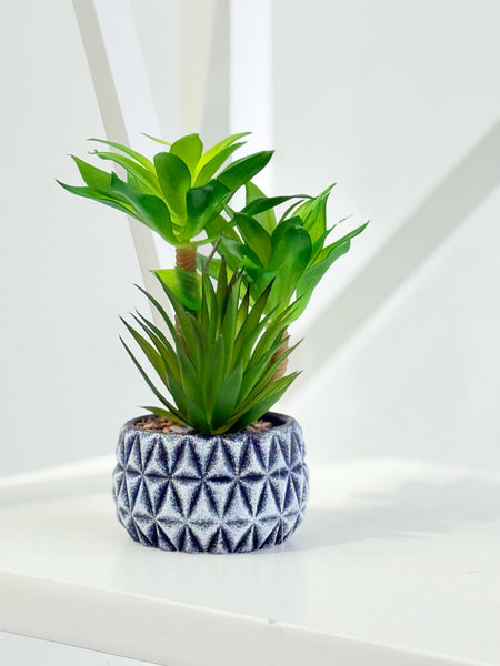 Faux succulent in a decorative diamond-pattern pot styled elegantly on a white surface.