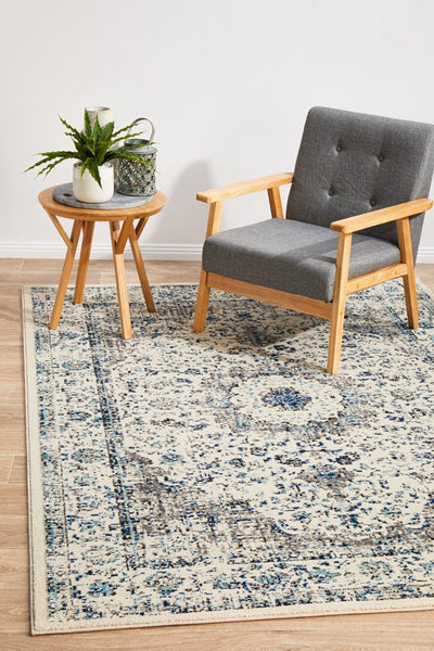 Evoke 21 White Rug styled in a modern living room with a grey armchair and wooden side table.