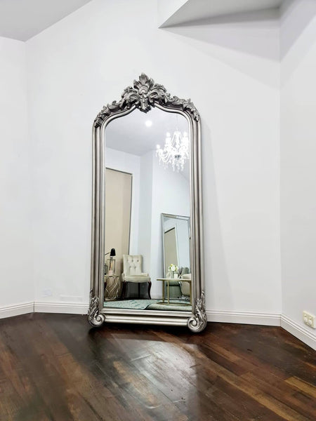 Silver ornate arch mirror styled in a modern room with chandelier and chair