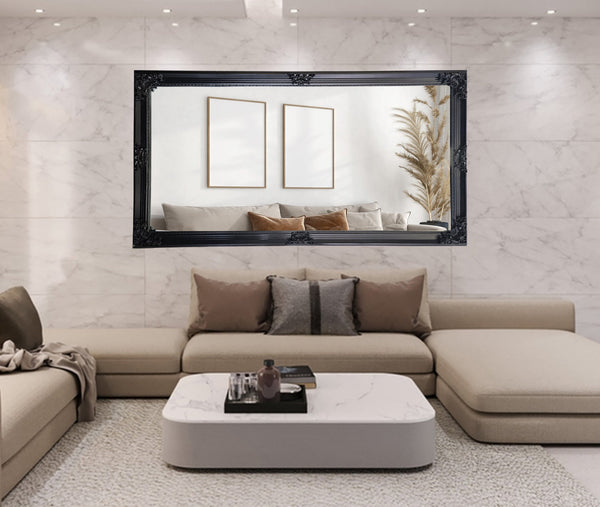 Black French provincial deluxe mirror styled horizontally above beige sectional with marble backdrop.