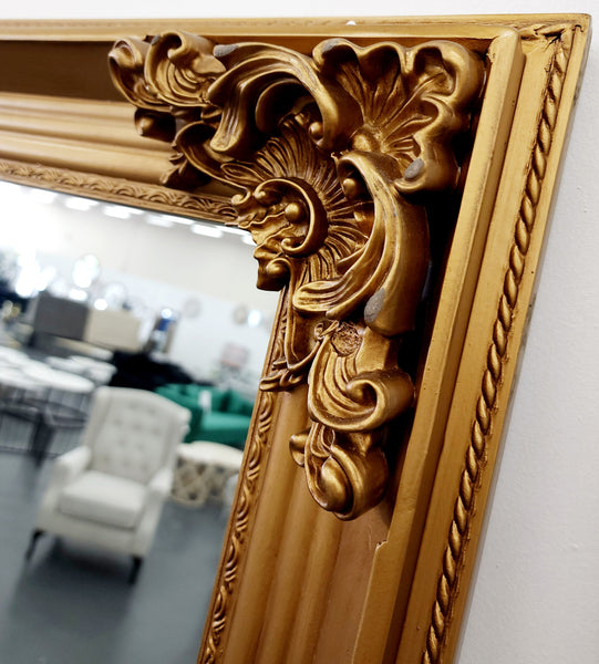 Close-up detail of French provincial deluxe mirror gold ornate carved antique finish frame corner.