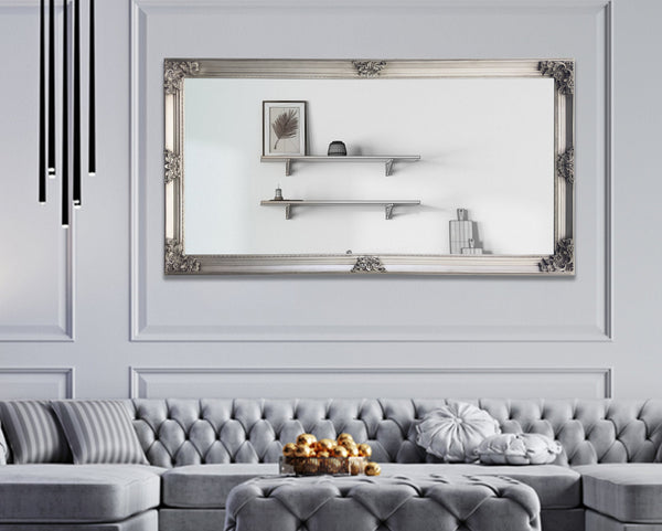 Silver French provincial deluxe mirror styled horizontally above sofa with tufted seating and shelves.