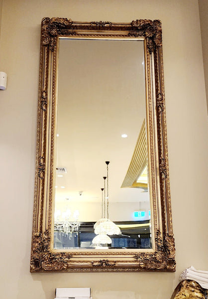 Gold French provincial LUX ornate mirror styled vertically in luxury space with chandelier lighting.