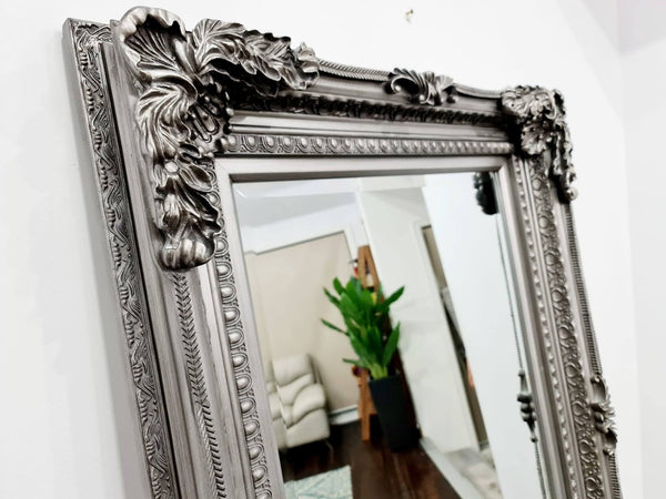 Close-up of French provincial LUX ornate silver mirror highlighting intricate carved frame detailing.