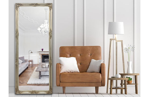 Champagne ornate French provincial mirror styled with tan armchair, floor lamp and wall panels.