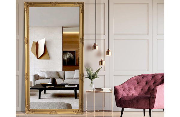 Gold French provincial ornate mirror styled in lounge with pink velvet chair and wall décor.