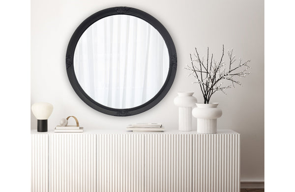 Black French provincial round mirror styled above console with vases, lamp and decorative accents.