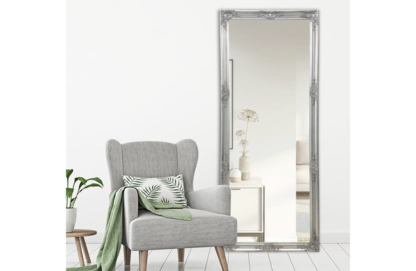 Silver ornate French provincial mirror styled with grey armchair, green cushion and indoor plant.