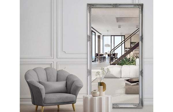 Antique silver French provincial ornate mirror styled with grey chair and modern white interiors.