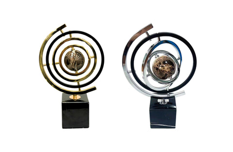 Black and gold, and black and silver globe table décor set on marble bases — a modern, elegant statement piece.