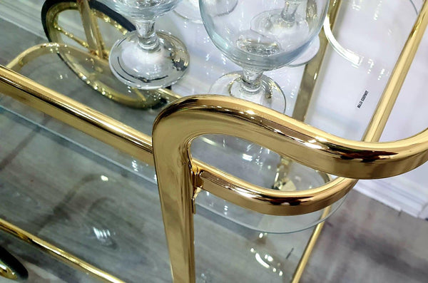 Close-up of gold bar trolley handle with glassware on display.