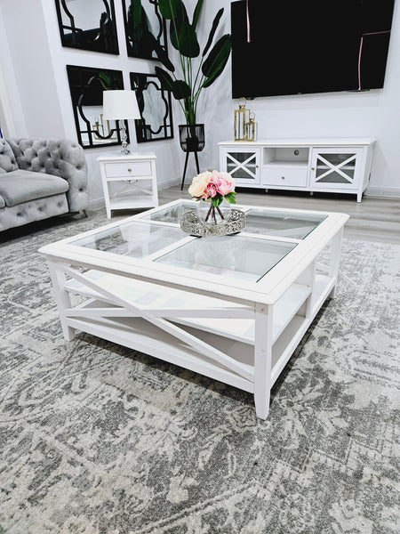 Hampton’s style white coffee table with glass top styled with décor in bright living room.