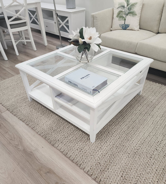 Hampton’s style white coffee table with glass top styled with flower vase in living room.