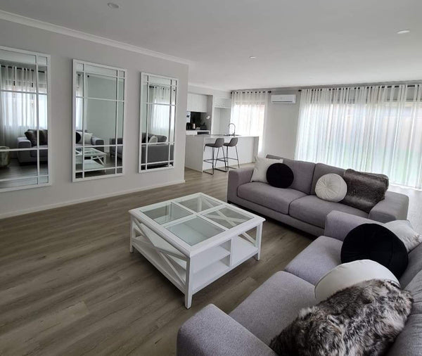 Hampton’s style white timber and glass coffee table placed centrally in modern living room.