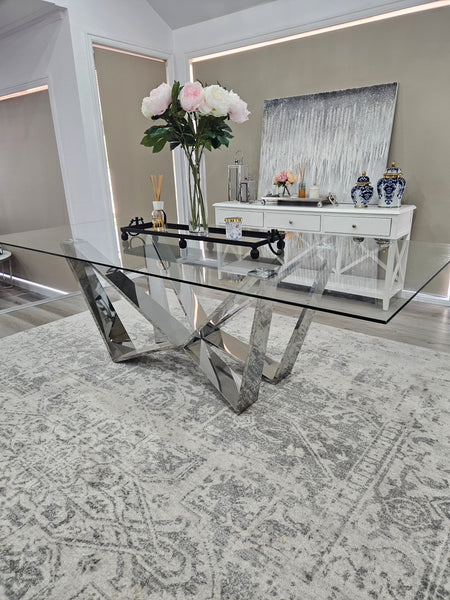 Lenox Dining Table with polished silver frame and glass top styled with modern décor.