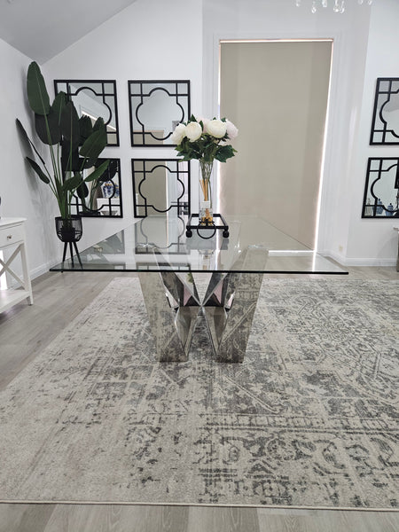 Lenox Dining Table silver stainless frame with clear tempered glass top styled in dining area.