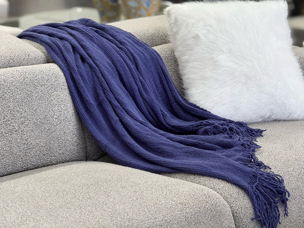 Stylish Levi Throw Rug Blanket in blue draped over a sofa, adding rich color and texture.